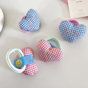 Detail of heart-shaped plaid hair ties with blue and pink embroidery and nice day labels