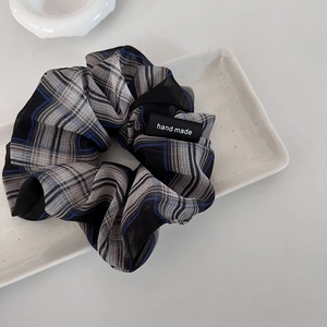 Retro grey plaid scrunchie with handmade label on minimalist white ceramic tray