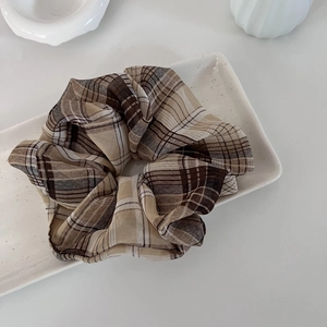Classic brown plaid oversized scrunchie placed on a white ceramic tray in a soft setting