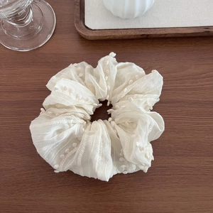 Elegant beige embroidered scrunchie with tassel and herringbone pattern for hair styling