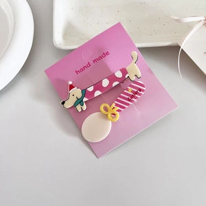 Détail de barrettes mignonnes en forme de teckel et cuillère sur carte rose
