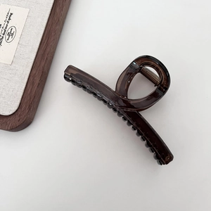 Dark brown translucent shark hair claw clip in a minimalist twisted ring design on white