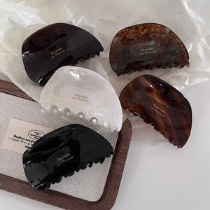 Macro shot of five acetate hair claws with gold Barrette La France text and tortoiseshell finish