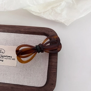 Close-up of tortoise shell pattern acetate bow hair clip on a minimalist wooden tray