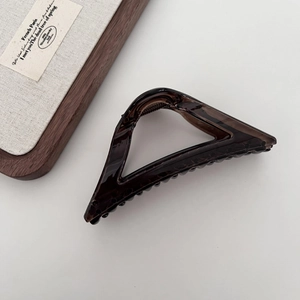 Detail view of transparent dark brown triangular hair claw clip on clean background