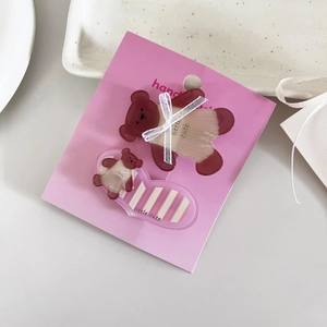 Détail de pinces à cheveux ourson marron mignon avec un nœud en ruban blanc sur un plat blanc