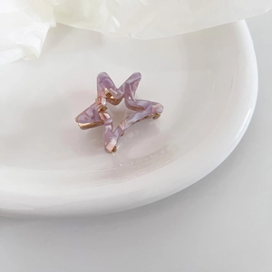 Detailed close-up of marble pattern acetate star hair claw clip with golden metal spring
