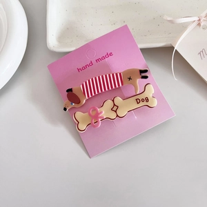 Gros plan de barrettes mignonnes chien et os sur une carte rose avec label fait main