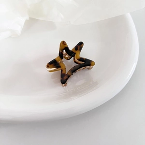 Macro view of star-shaped acetate hair claw with tortoise shell pattern and golden spring