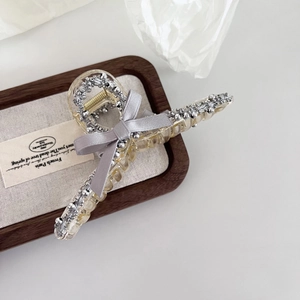 Détail d'une pince à cheveux avec nœud en soie grise et bordure en perles argent