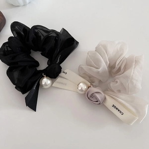 Detail of organza scrunchies in black and beige with pearls and fabric rose decoration