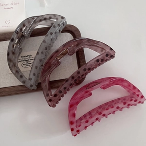 Close-up of semi-transparent polka dot hair claws in gray, brown and rose pink on a tray