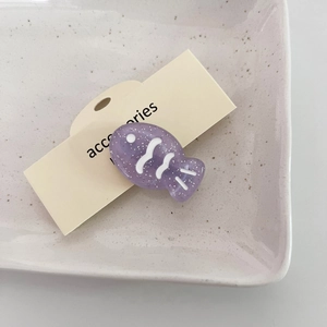 Pinza para el pelo con forma de pez morado brillante en resina sobre tarjeta de cartón