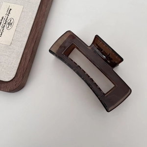Macro detail of dark brown rectangle hollow claw clip with smooth acrylic texture