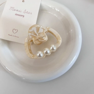 Détail de la pince à cheveux en acétate avec perles et texture effet marbre