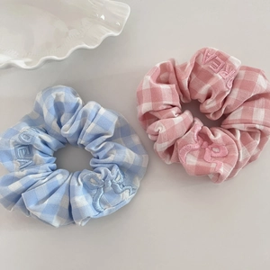 Detailed view of gingham scrunchies with bow embroidery and dream text on fabric