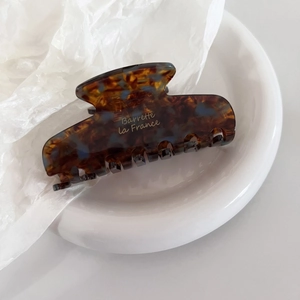 Detailed macro view of an amber tortoiseshell hair claw clip with blue marble accents