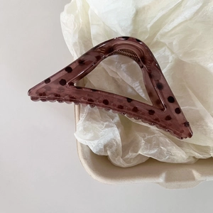 Detail view of triangular resin hair claw clip with dark polka dots and spring mechanism