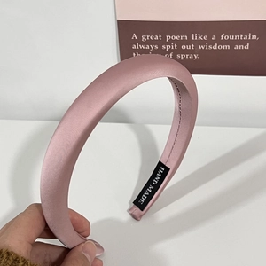 Détail d'un serre-tête rembourré en satin rose fait main avec une texture lisse