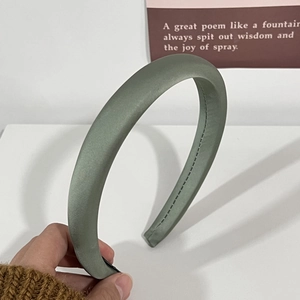 Détail du serre-tête en satin vert gris montrant le rembourrage et les coutures fines