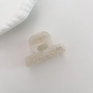 Détail d'une pince à cheveux en acétate marbré beige avec lettrage Barrette La France