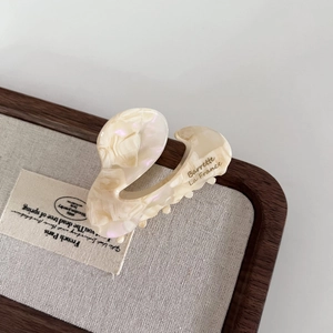 Detail view of pearlescent beige acetate hair claw clip with French lettering