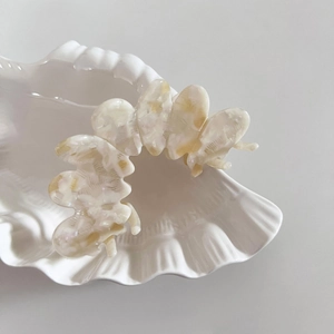 Elegant cream marble acetate hair claw clip with large wave design on shell ceramic tray