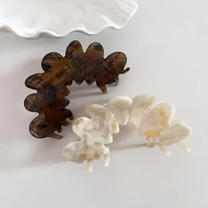Close-up of two elegant acetate hair claws in dark brown and creamy marble patterns