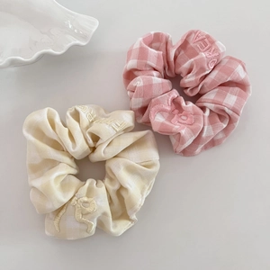 Close-up of pink and beige plaid scrunchies with intricate embroidery on cotton fabric