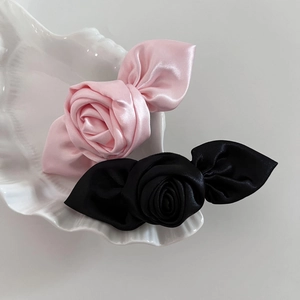 Detaillierte Nahaufnahme von rosa und schwarzen Satin-Rosen-Haarspangen auf Keramikschale