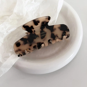 Close-up of tortoise shell acetate hair claw clip with Barrette la France logo in a ceramic bowl