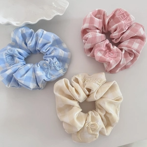 Detailed view of plaid scrunchies in blue, pink and beige with exquisite floral embroidery