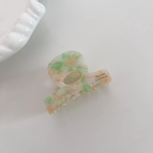 Détail d'une pince à cheveux en acétate avec marbrure verte et rose et gravure Barrette