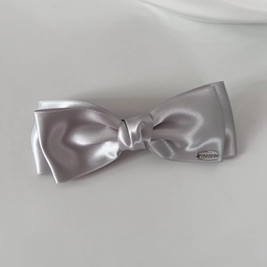 Elegant silver satin double-layer bow hair clip with polished metal brand tag for women