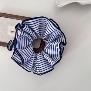 Détail de chouchou en tissu à rayures bleues et blanches avec bordure brodée bleu marine