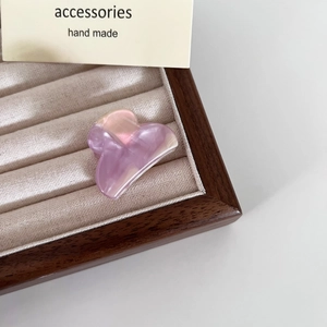Dettaglio di piccola molletta in acetato marmorizzato viola su vassoio in velluto