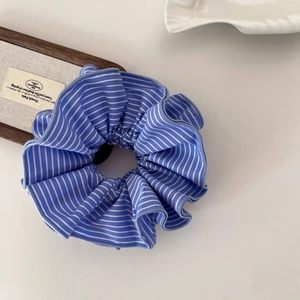 Chouchou en tissu à rayures bleues et blanches sur un plateau décoratif en bois