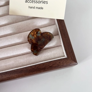 Dettaglio del fermaglio per capelli in acetato tartarugato su vassoio in velluto
