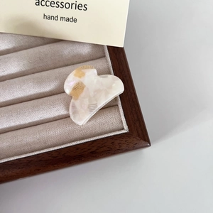 Dettaglio di mini mollette per capelli in acetato marmorizzato in un portagioie