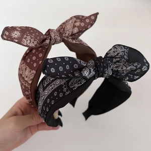 Close-up of black and brown paisley pattern wide bow headbands with fabric texture