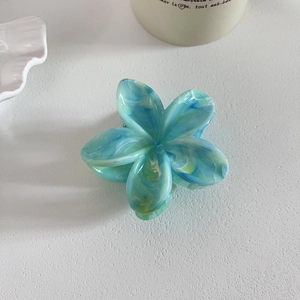 Pince à cheveux fleur avec motif marbré bleu et vert sur fond blanc épuré