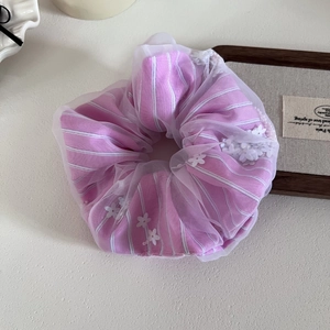 Dettaglio scrunchie a righe rosa con tulle bianco e piccole decorazioni floreali
