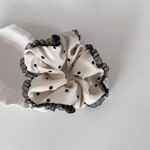 Polka dot satin scrunchie with black lace trim and brand label in white and black