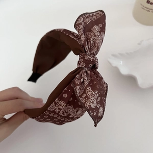 Close-up of brown paisley bow headband showing soft fabric texture and flexible design