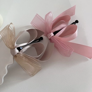Détail de barrettes à nœuds en tulle rose et champagne avec rubans satinés