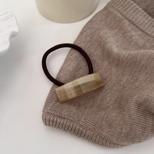 Detail of acetic acid hair tie with France handmade text on marble textured rectangle