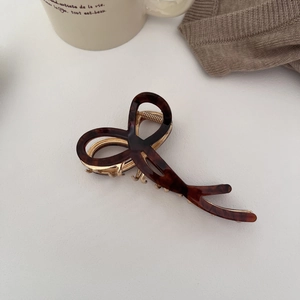 Detail of large dark brown tortoiseshell hair claw with gold metal spring for thick hair