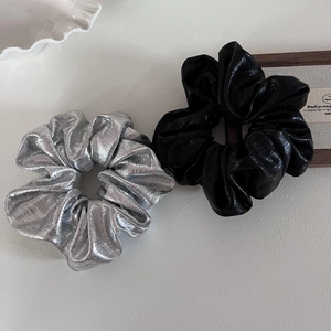 Detail of silver and black metallic scrunchies with pleated texture and elastic grip
