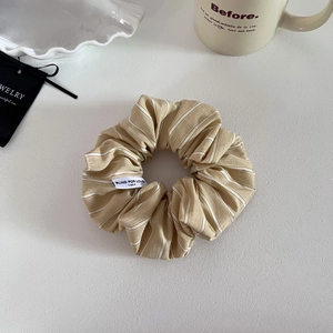 Elegant striped khaki scrunchie for low ponytail styling with detailed fabric texture