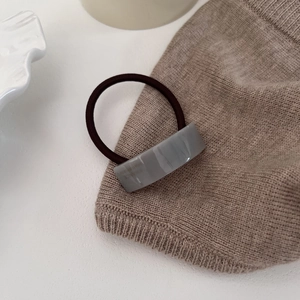 Detailed macro of a grey resin rectangle arc hair tie with a coffee brown elastic cord